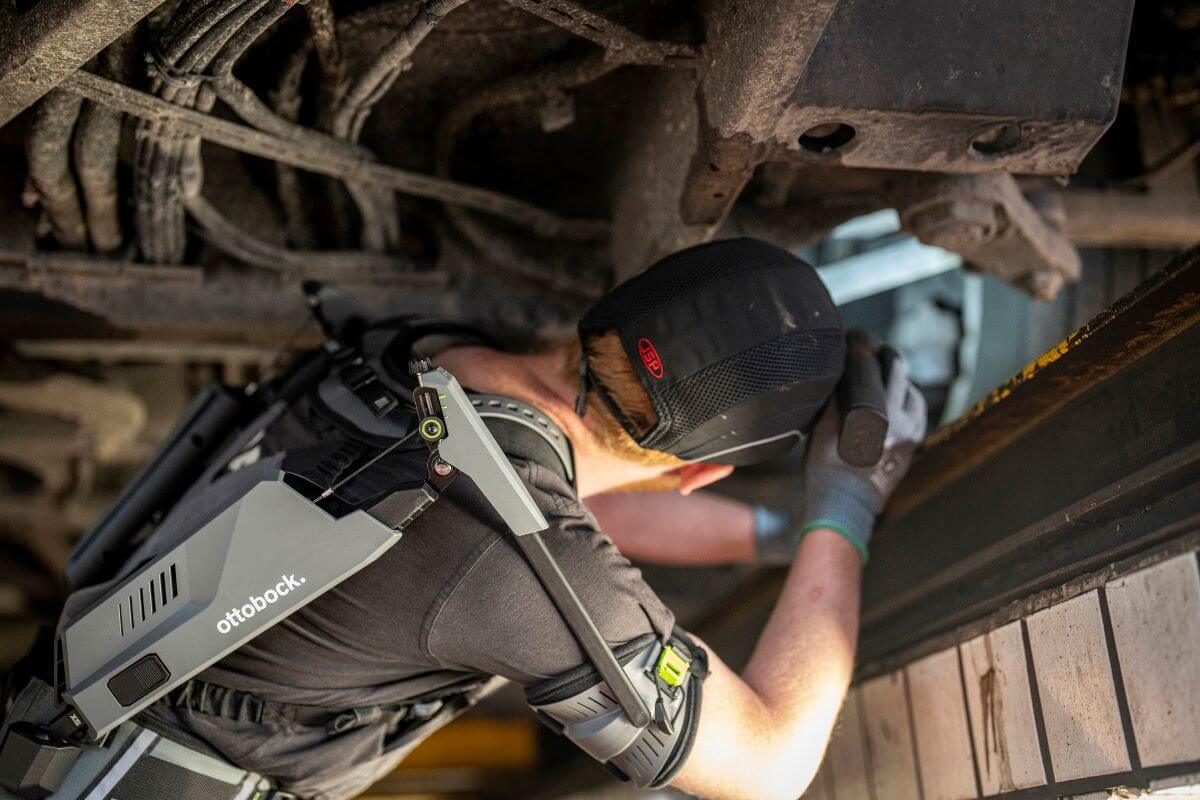 SUITX worker using an exoskeleton below a vehicle